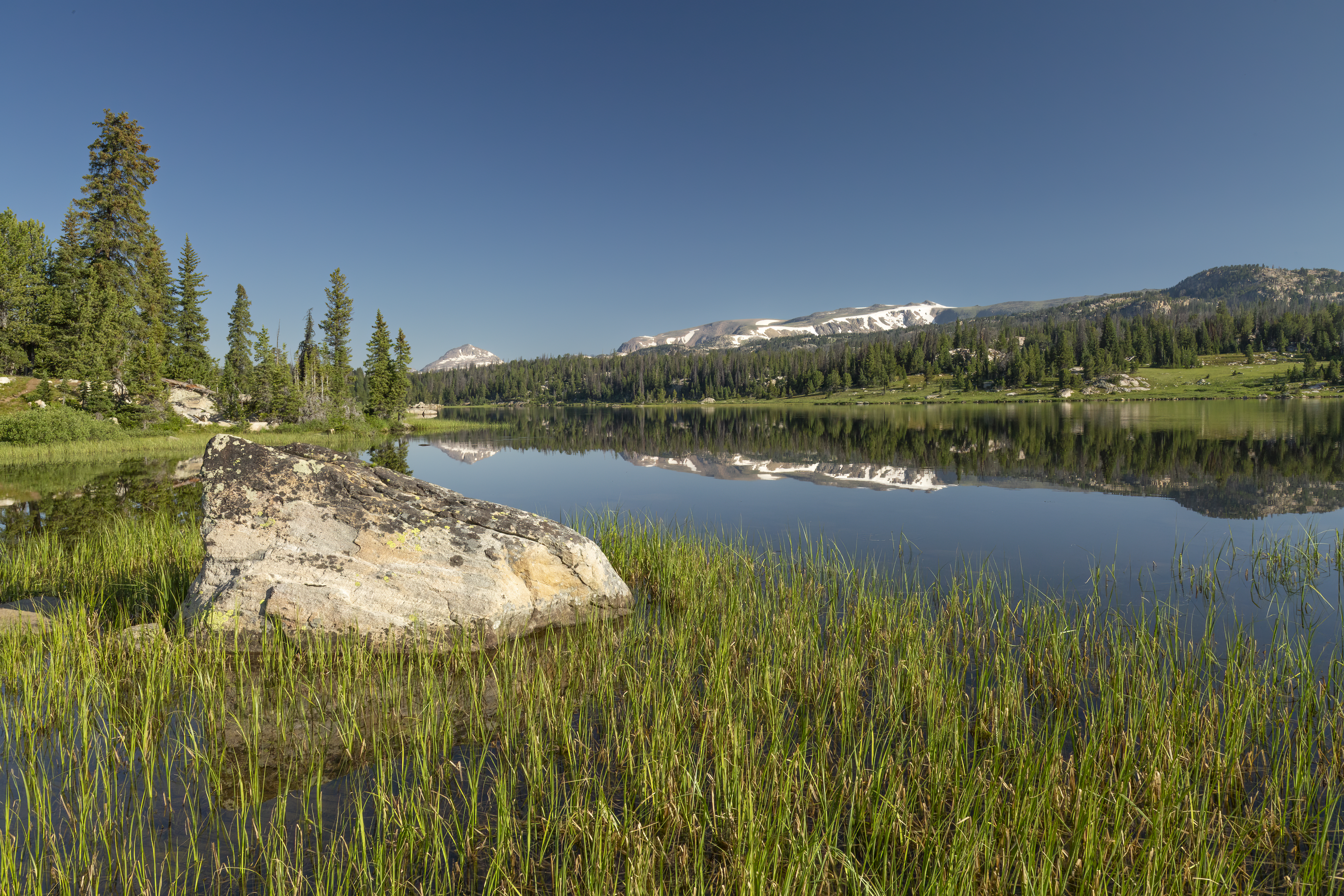 a calm reflective river showing the mountains in the background in the foreground